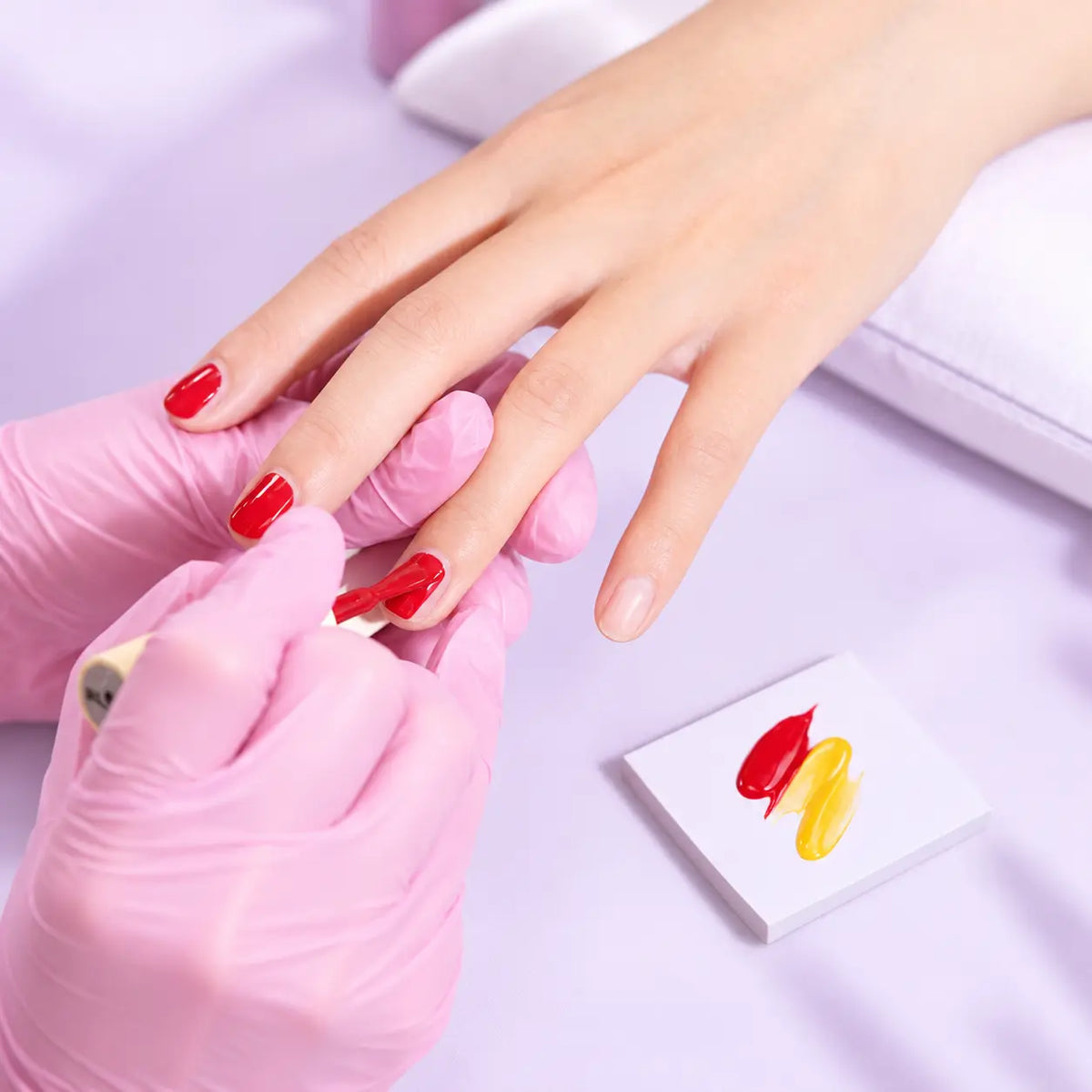 Hand using a disposable nail art palette paper sheet for gel polish